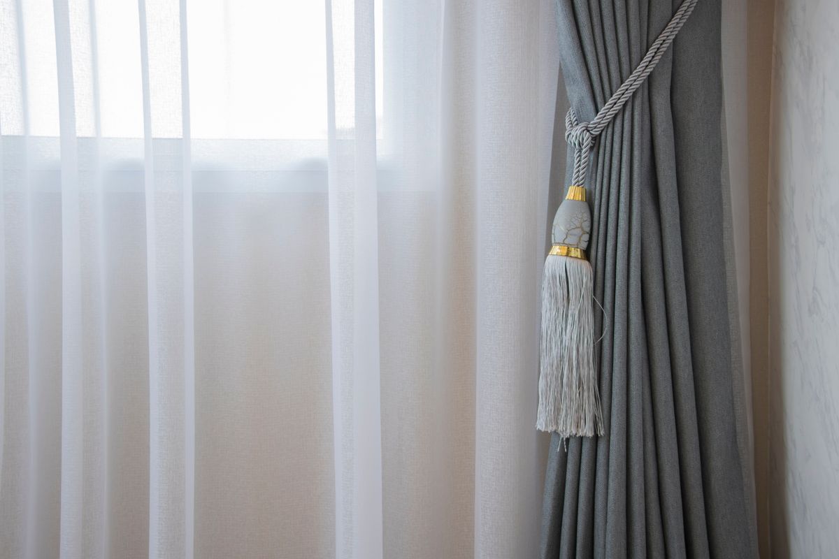 A tasselled tieback dressing a curtain by a sunlit window